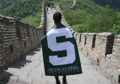 Student with an MSU flag walking on the Great Wall of China