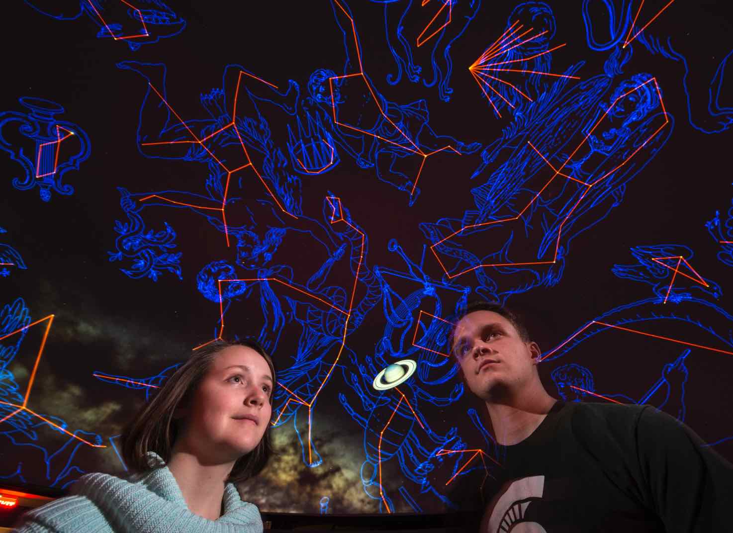 People gaze at constellations on the ceiling of the planetarium)