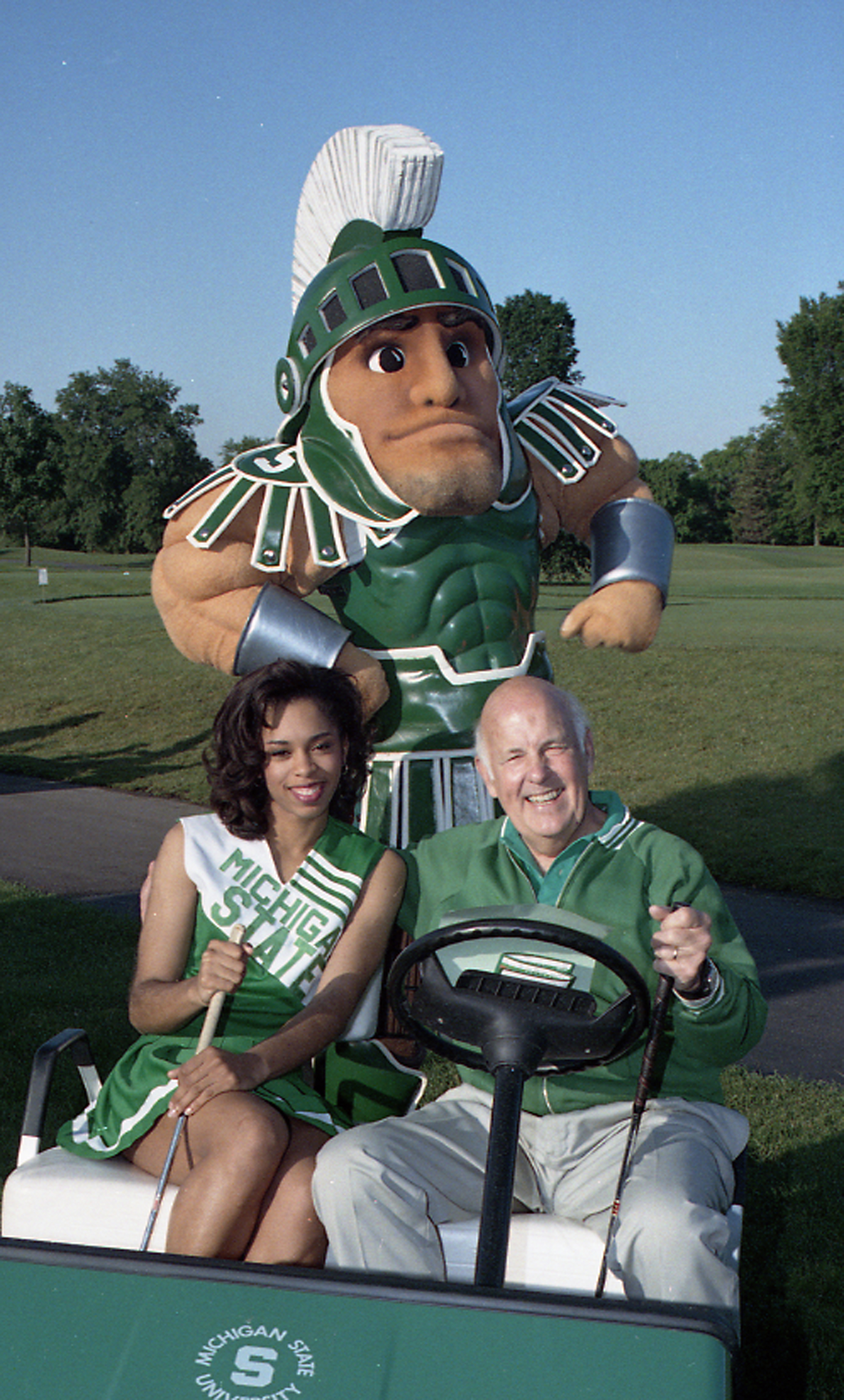 Guyer poses with Sparty and a student during a golf outing.