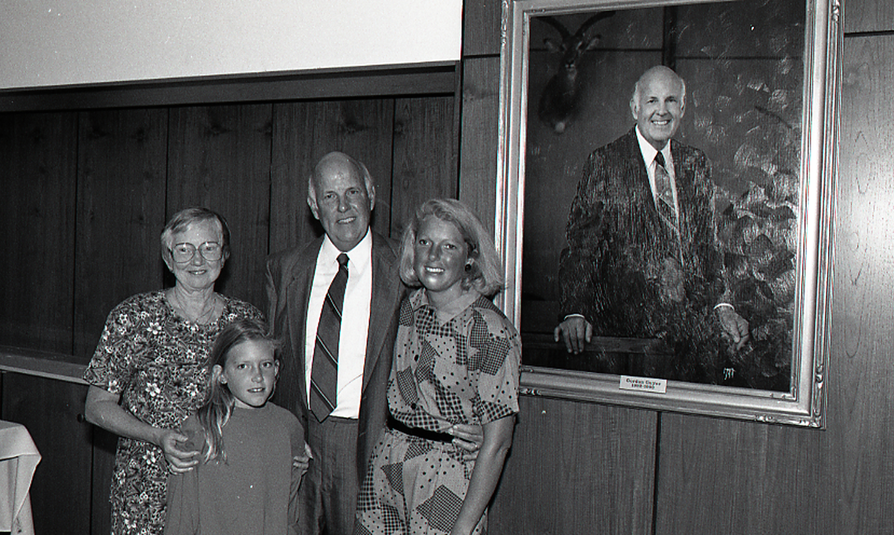 Guyer poses with family in front of his portrait painting at the John A. Hannah administration building at MSU. Photo courtesy of MSU Archives.